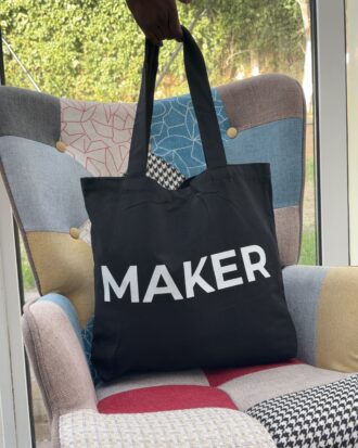 Black canvas tote bag with white “Maker” lettering and shoulder handles