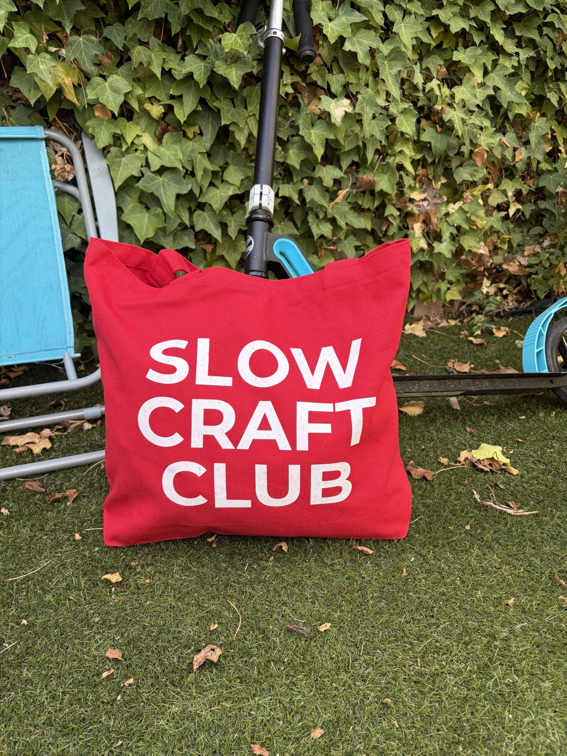Red canvas tote bag with white “Slow Craft Club” lettering.