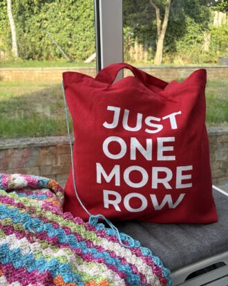 Red canvas tote bag with white “Just One More Row” lettering.